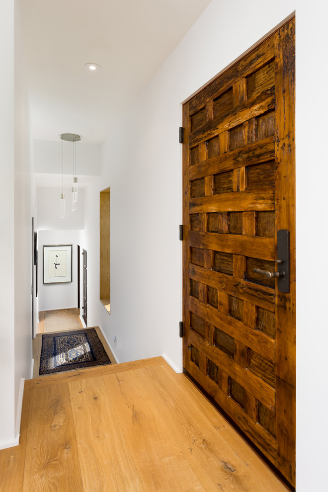 This is an example of a medium sized mediterranean vestibule in Los Angeles with white walls, light hardwood flooring, a single front door, a medium wood front door and yellow floors.