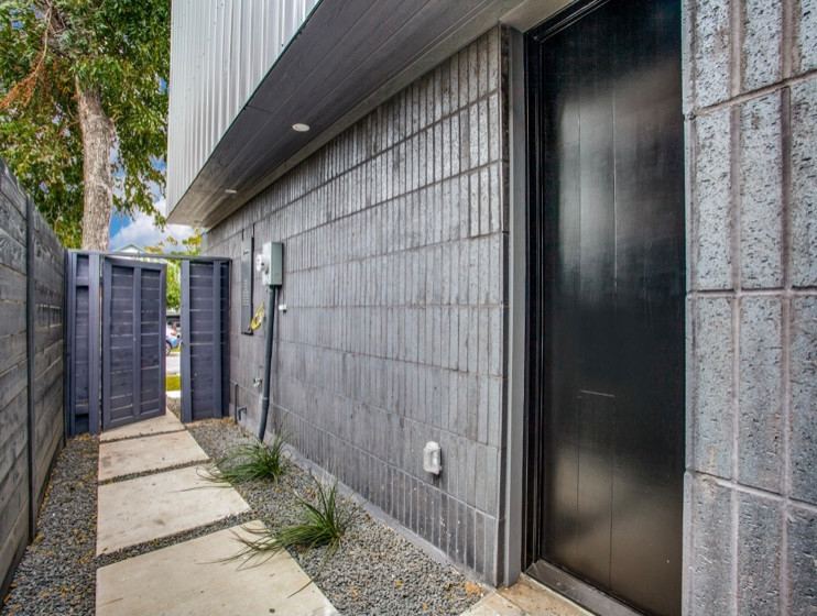 Ejemplo de puerta principal moderna con paredes grises, suelo de cemento, puerta simple, puerta negra, suelo gris y ladrillo