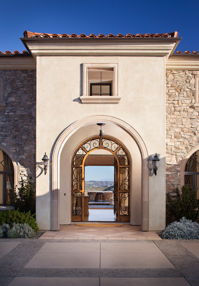 На фото: большая входная дверь в средиземноморском стиле с бежевыми стенами, бетонным полом, двустворчатой входной дверью и стеклянной входной дверью
