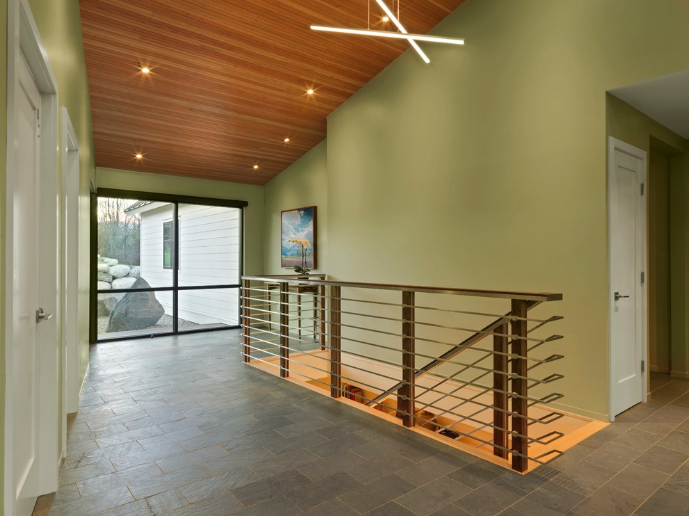 Esempio di un grande corridoio moderno con pareti verdi, pavimento in ardesia, una porta singola e una porta in vetro