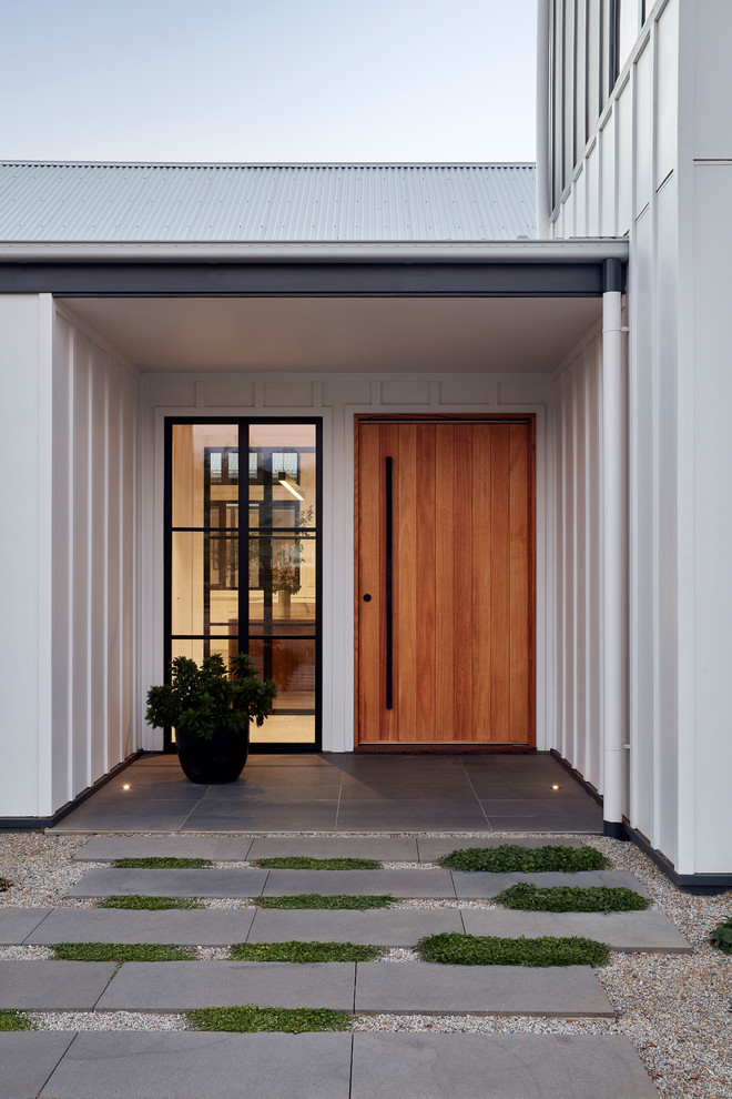 Idee per una porta d'ingresso country di medie dimensioni con pareti bianche, pavimento in cemento, una porta a pivot, una porta in legno chiaro e pavimento bianco
