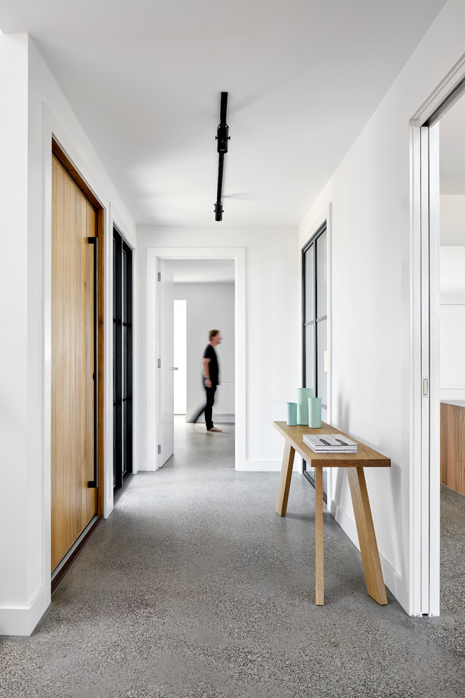 メルボルンにあるラグジュアリーな中くらいなカントリー風のおしゃれな玄関ドア (白い壁、コンクリートの床、淡色木目調のドア、白い床) の写真