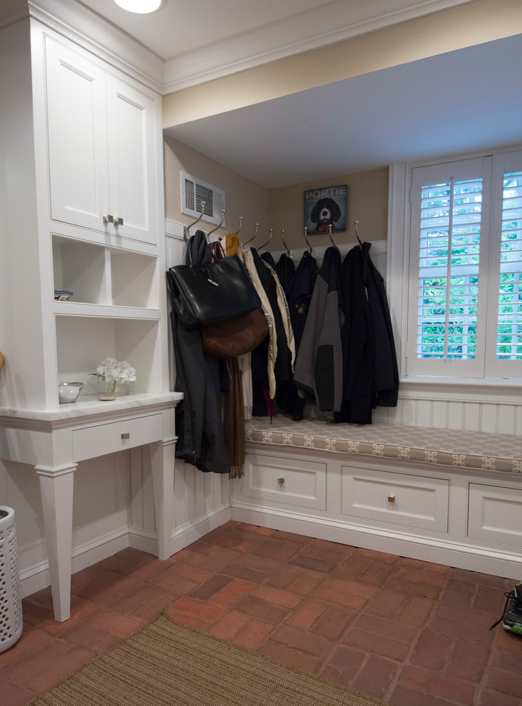 This is an example of a medium sized traditional boot room in Philadelphia with beige walls, brick flooring and red floors.