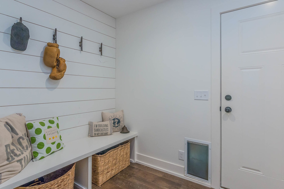 Réalisation d'une entrée chalet de taille moyenne avec un vestiaire, un mur blanc, parquet foncé, une porte simple et une porte blanche.