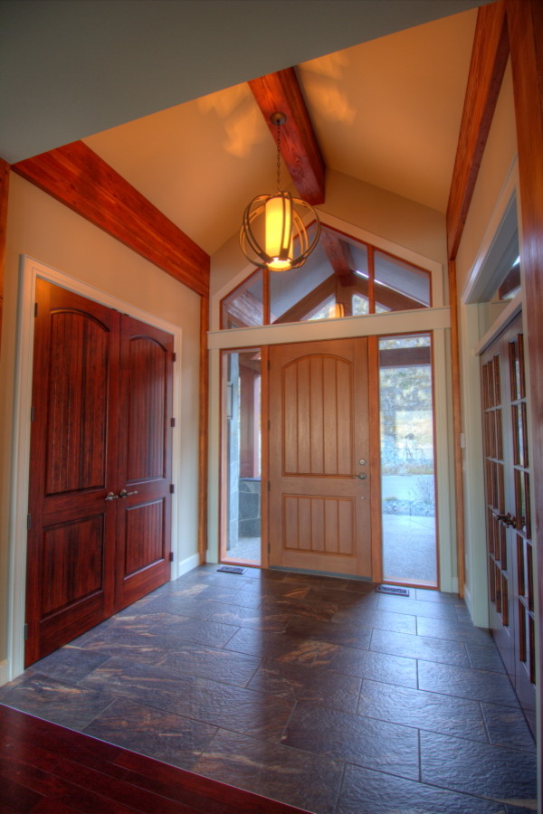На фото: входная дверь среднего размера в современном стиле с бежевыми стенами, полом из керамогранита, одностворчатой входной дверью и входной дверью из темного дерева