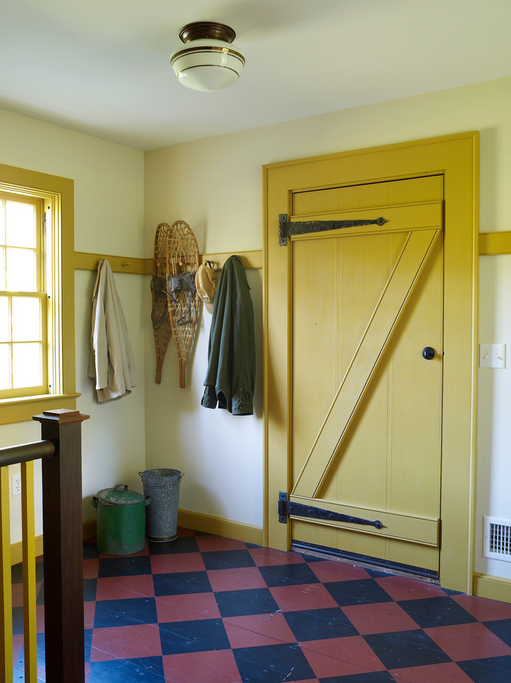 This is an example of a farmhouse entrance in New York with a single front door, a yellow front door and feature lighting.
