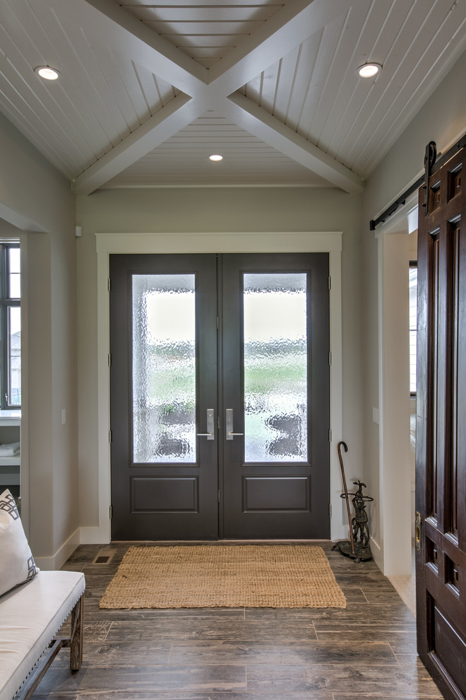 На фото: входная дверь в стиле рустика с полом из керамогранита и двустворчатой входной дверью с
