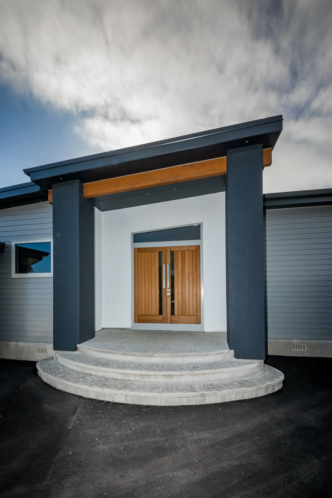 Imagen de puerta principal costera grande con suelo de cemento, puerta doble y puerta de madera en tonos medios