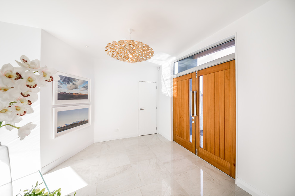 Ejemplo de puerta principal marinera grande con paredes blancas, suelo de mármol, puerta doble, puerta de madera en tonos medios y suelo blanco