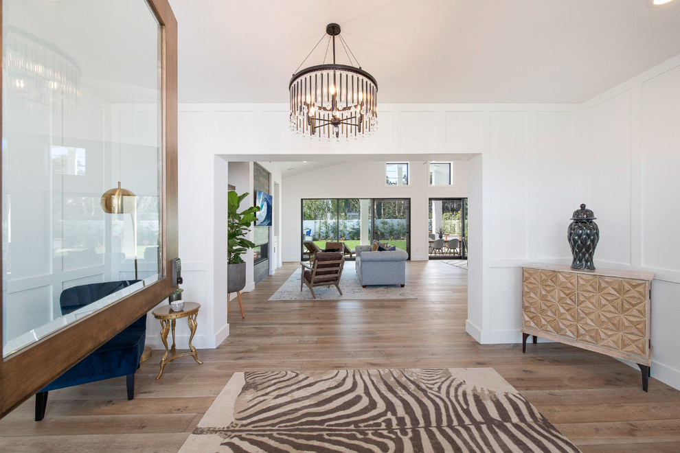 Große Landhaus Haustür mit weißer Wandfarbe, braunem Holzboden, Klöntür, brauner Haustür und braunem Boden in Orange County