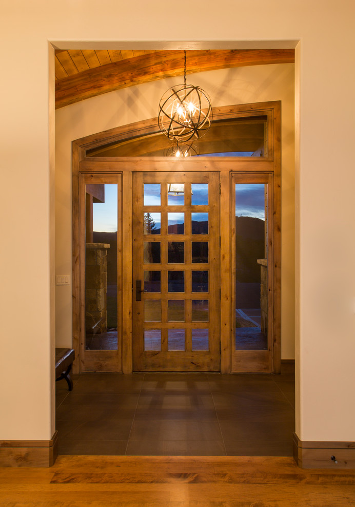 Ejemplo de vestíbulo rústico de tamaño medio con paredes beige, suelo de madera oscura, puerta simple, puerta de madera oscura y suelo marrón
