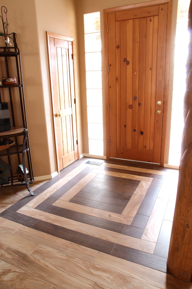 アルバカーキにある中くらいなサンタフェスタイルのおしゃれな玄関ドア (ベージュの壁、磁器タイルの床、木目調のドア、マルチカラーの床) の写真