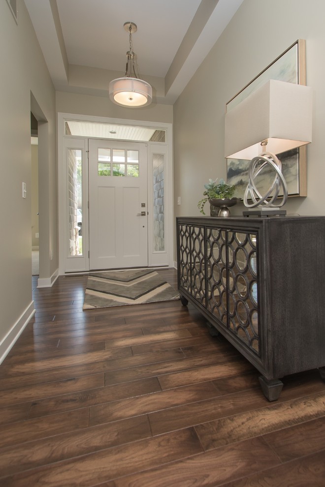 Example of a mid-sized transitional dark wood floor and brown floor entryway design in Grand Rapids with beige walls and a white front door