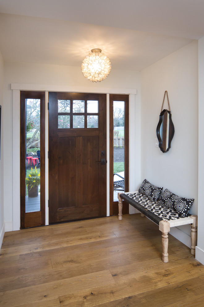Réalisation d'un petit hall d'entrée champêtre avec un mur blanc, un sol en bois brun, une porte simple, une porte en bois foncé et un sol marron.