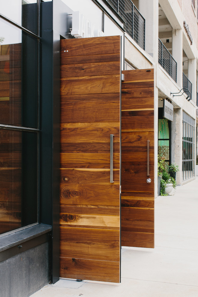 Réalisation d'une grande porte d'entrée minimaliste avec sol en béton ciré, une porte double et une porte en bois brun.