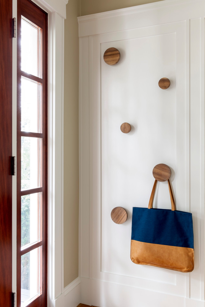 Aménagement d'un petit hall d'entrée classique avec un mur blanc, parquet clair, une porte simple et une porte en bois foncé.