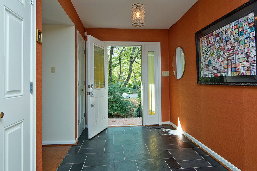 ローリーにあるお手頃価格の中くらいなミッドセンチュリースタイルのおしゃれな玄関ロビー (オレンジの壁、コルクフローリング、白いドア、ベージュの床) の写真