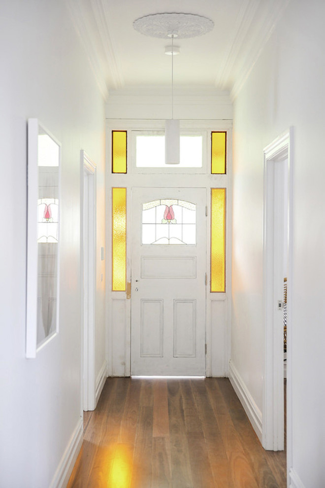 Cette photo montre une grande entrée éclectique avec un couloir, un mur blanc, parquet foncé, une porte simple et une porte blanche.
