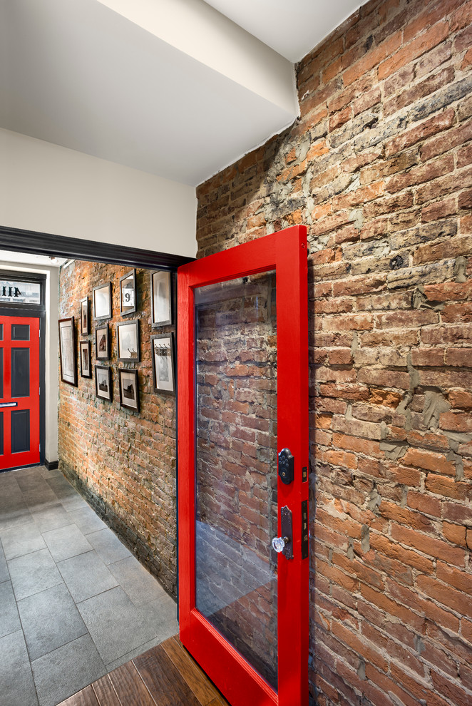 Ispirazione per un grande corridoio industriale con pareti rosse, pavimento in ardesia, una porta singola e una porta rossa