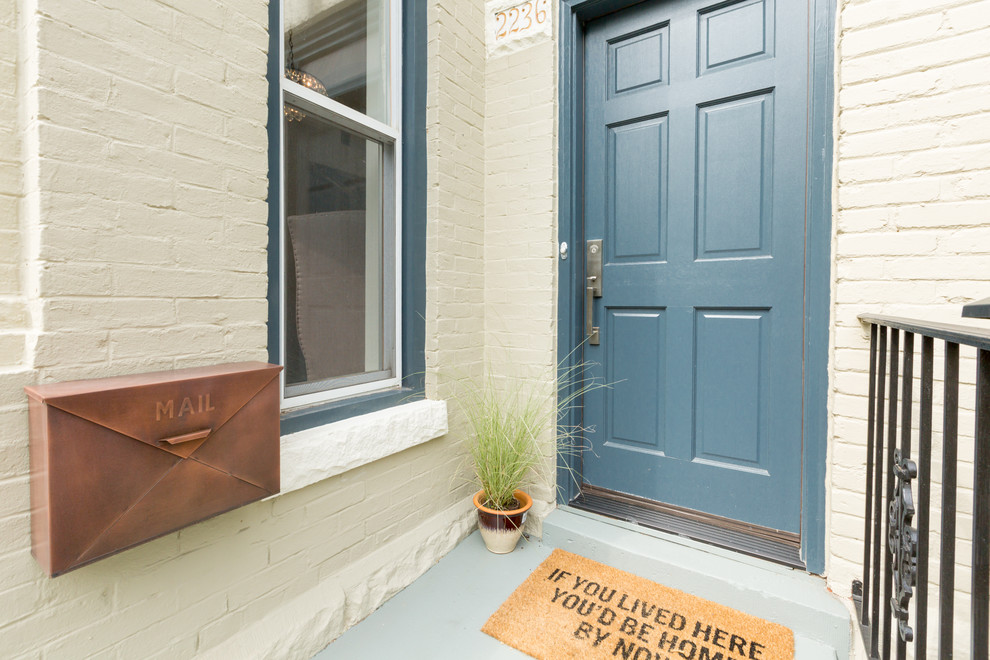 Ejemplo de puerta principal actual pequeña con paredes beige, suelo de cemento, puerta simple y puerta azul