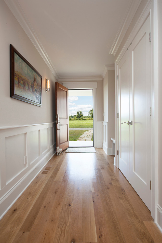 Réalisation d'une entrée minimaliste avec un couloir, un mur blanc, un sol en bois brun et une porte en bois brun.