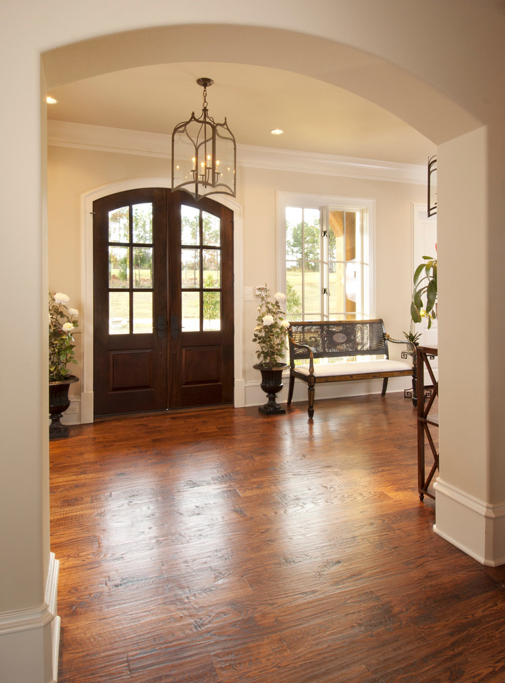 Large elegant medium tone wood floor entryway photo in Dallas with beige walls and a dark wood front door