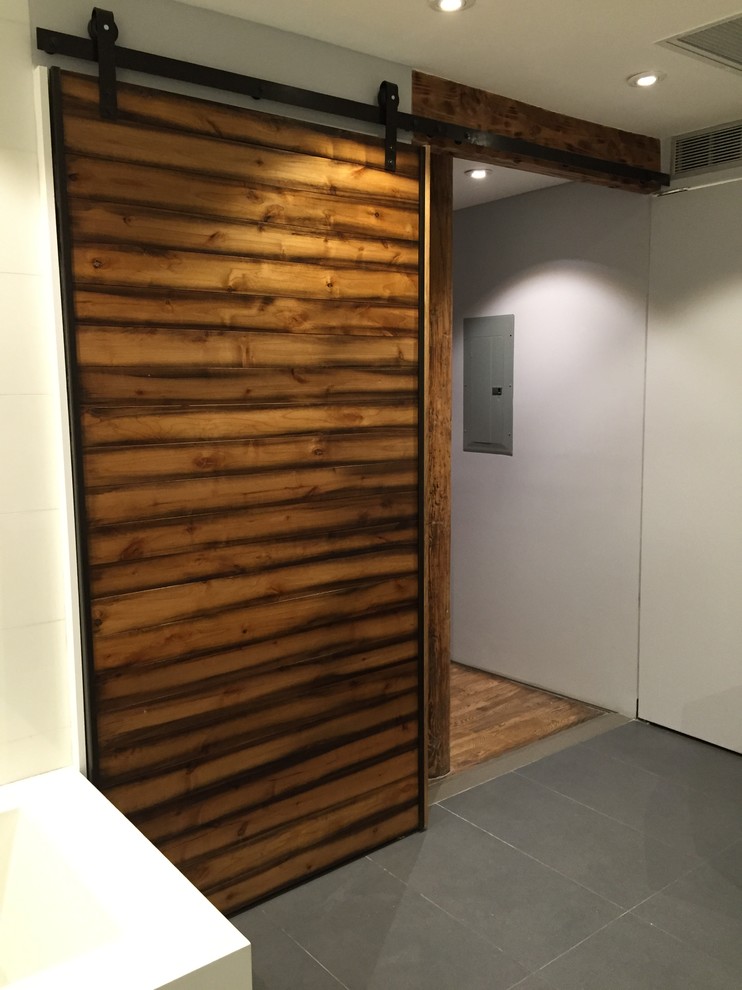На фото: большая узкая прихожая в стиле лофт с коричневыми стенами, бетонным полом, одностворчатой входной дверью, входной дверью из дерева среднего тона и серым полом