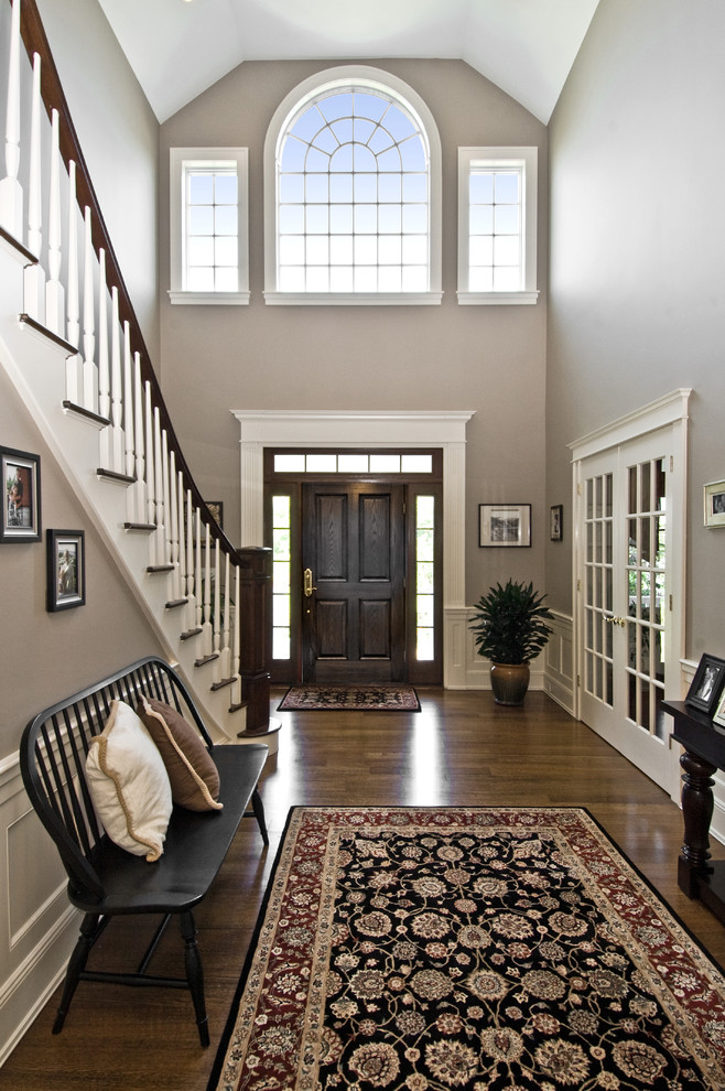 Klassisches Foyer mit dunkler Holzhaustür, beiger Wandfarbe, dunklem Holzboden, Einzeltür und braunem Boden in New York