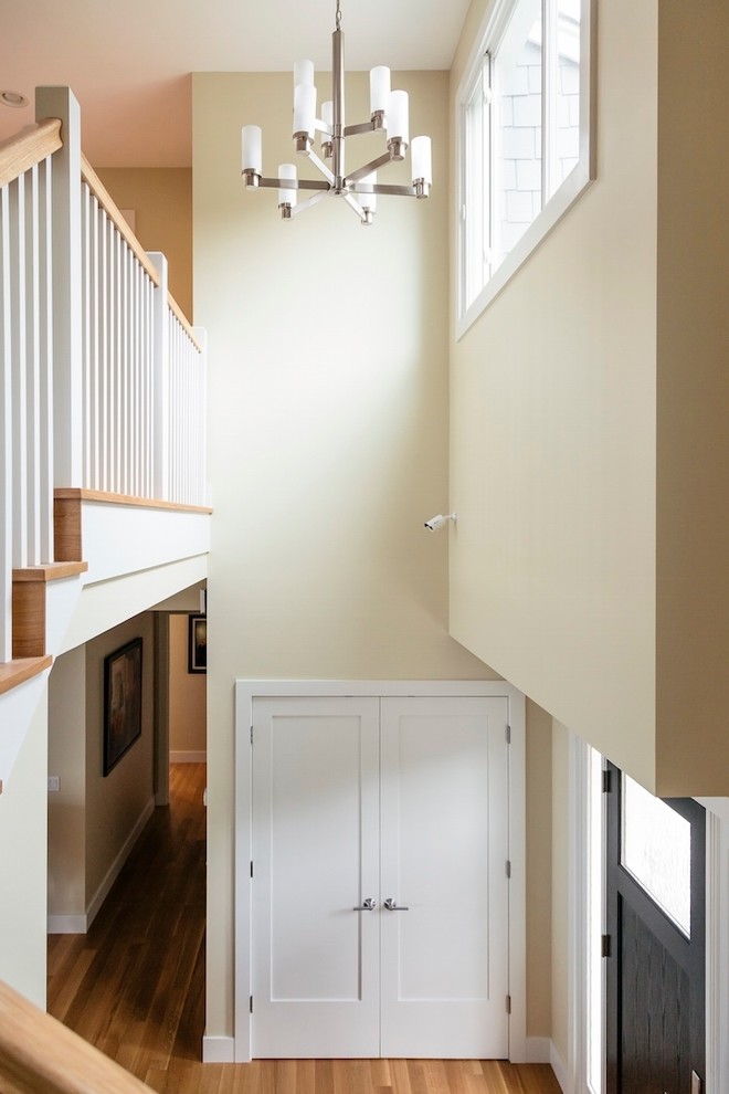 Idée de décoration pour un hall d'entrée design de taille moyenne avec un mur beige, un sol en bois brun, une porte simple et une porte noire.