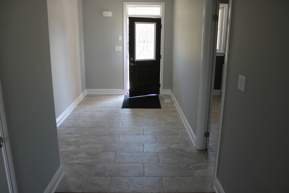 Réalisation d'une entrée tradition de taille moyenne avec un couloir, un mur gris, un sol en carrelage de céramique, une porte simple et une porte noire.