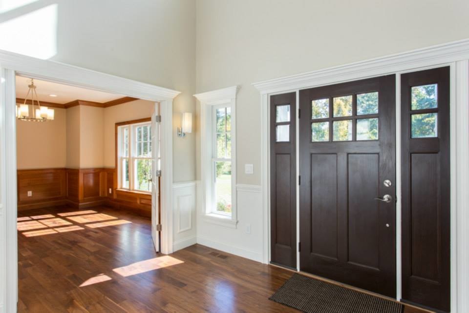Inspiration for a large timeless medium tone wood floor entryway remodel in New York with beige walls and a dark wood front door