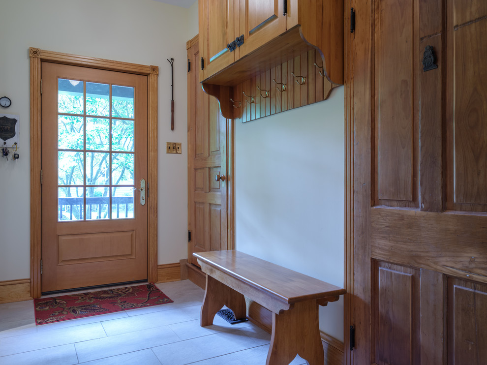 Idée de décoration pour une entrée tradition de taille moyenne avec un vestiaire, un mur blanc, une porte simple, une porte en bois clair, un sol blanc et un sol en carrelage de céramique.