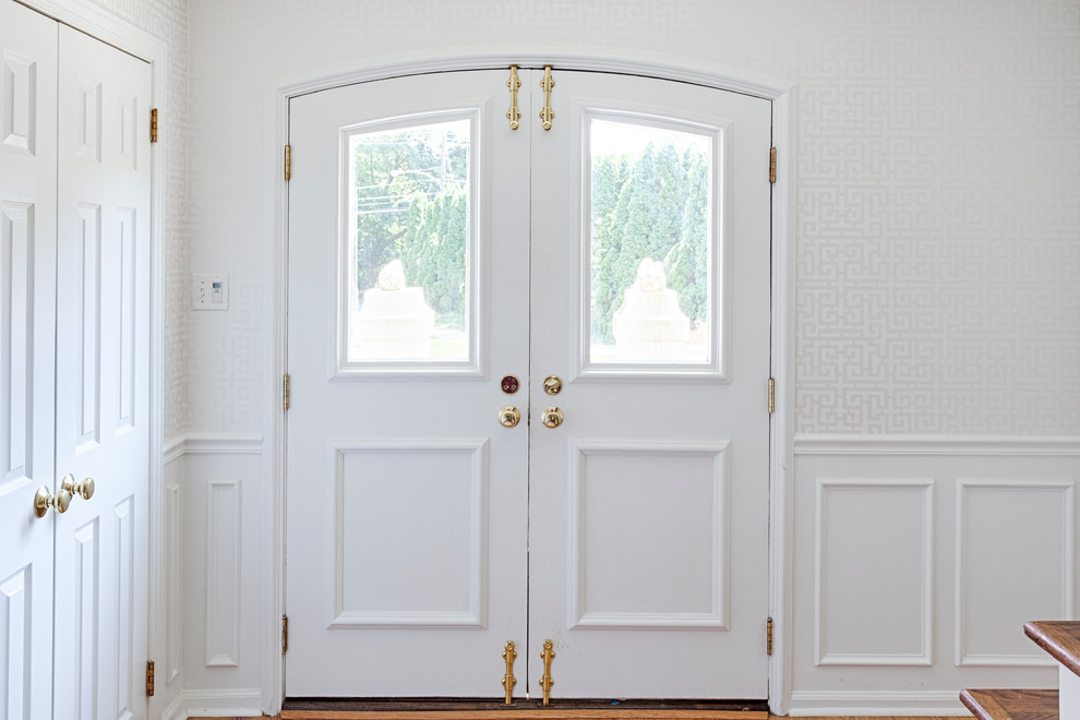 Idée de décoration pour une porte d'entrée tradition de taille moyenne avec un mur blanc, un sol en bois brun, une porte double, une porte blanche et un sol marron.