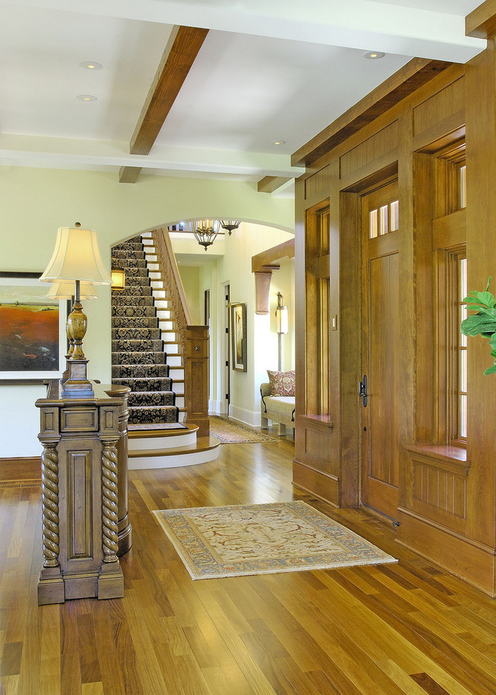 Esempio di un ingresso o corridoio tradizionale con pareti gialle, pavimento in legno massello medio, una porta singola e una porta in legno bruno
