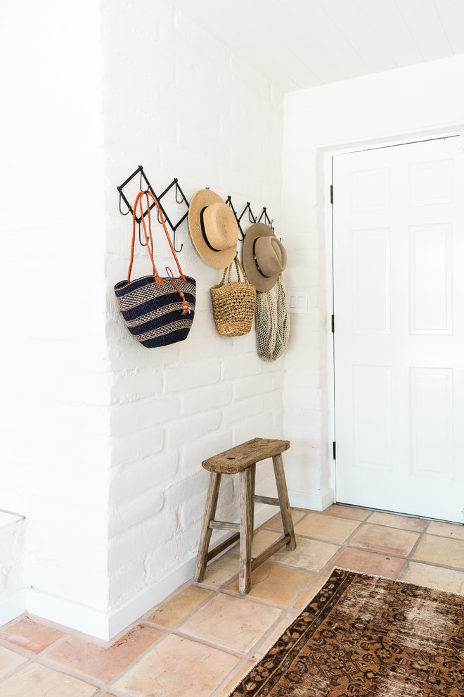 Imagen de entrada de estilo americano con paredes blancas, suelo de baldosas de terracota, puerta simple y puerta blanca