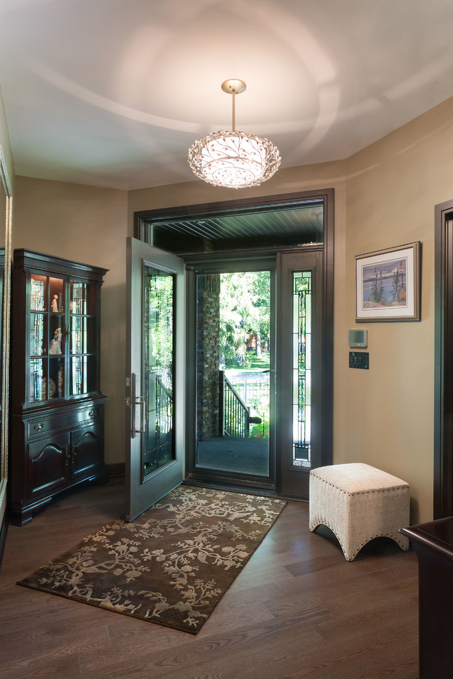 Modelo de puerta principal clásica renovada grande con paredes beige, suelo de madera en tonos medios, puerta simple, puerta de madera oscura y suelo marrón