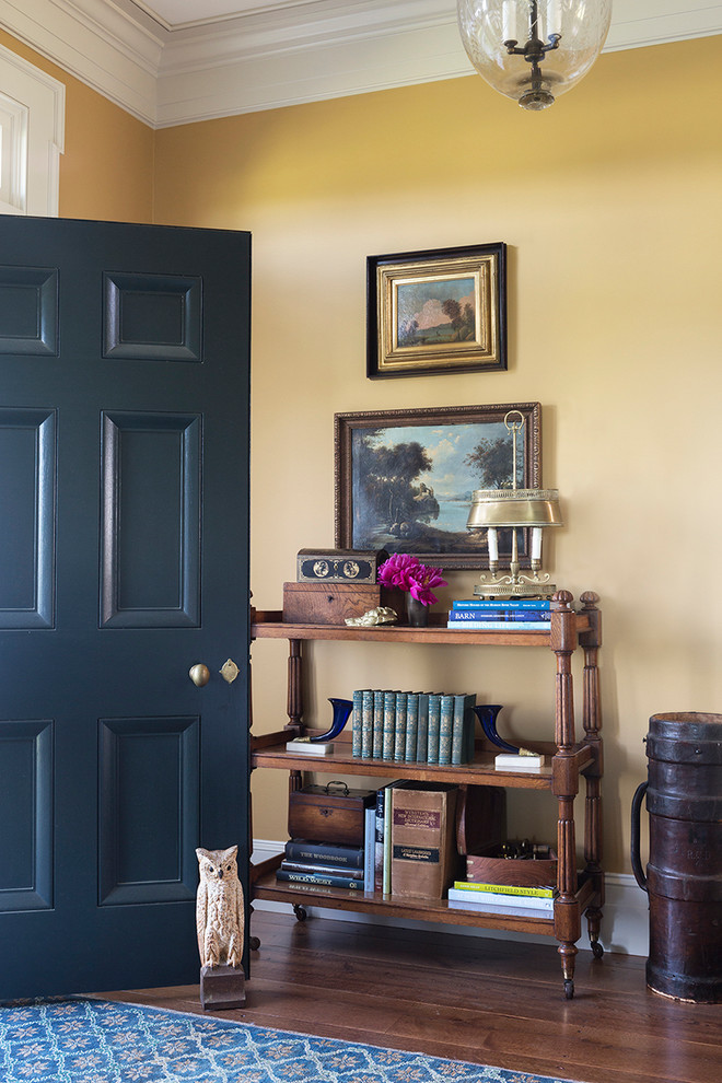 Imagen de puerta principal campestre grande con paredes amarillas, suelo de madera en tonos medios, puerta simple, puerta azul y suelo marrón