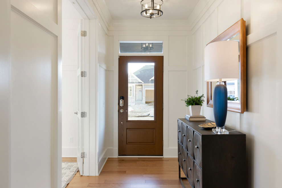 Idée de décoration pour un hall d'entrée tradition avec un mur gris, un sol en bois brun, une porte simple, une porte en bois foncé et du lambris.