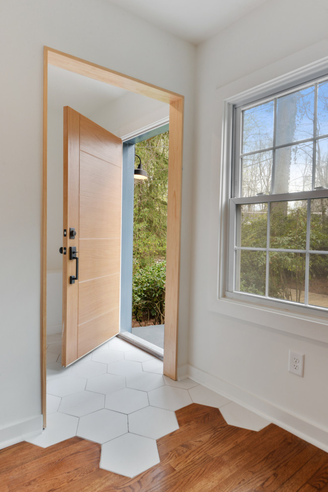 Ispirazione per una piccola porta d'ingresso minimalista con pareti bianche, pavimento con piastrelle in ceramica, una porta singola, una porta in legno chiaro e pavimento bianco