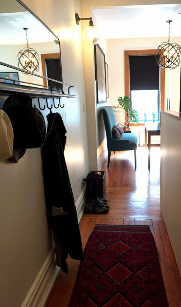 Foto di un piccolo corridoio boho chic con pareti bianche, pavimento in legno massello medio, una porta singola, una porta in metallo e pavimento marrone