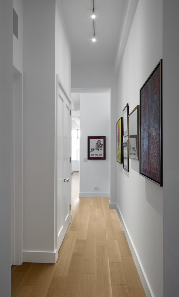 Foto di un corridoio contemporaneo di medie dimensioni con pareti bianche, parquet chiaro e pavimento beige