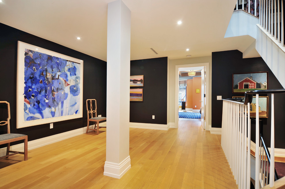 Example of a large trendy light wood floor foyer design in New York with black walls