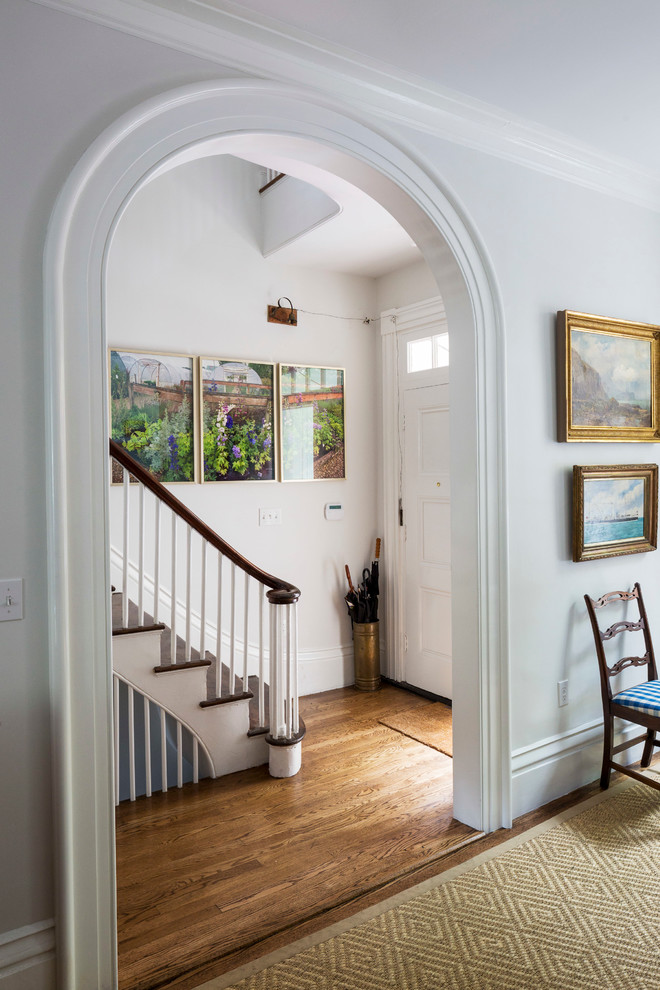 Example of a mid-sized classic medium tone wood floor entryway design in Boston with white walls and a white front door