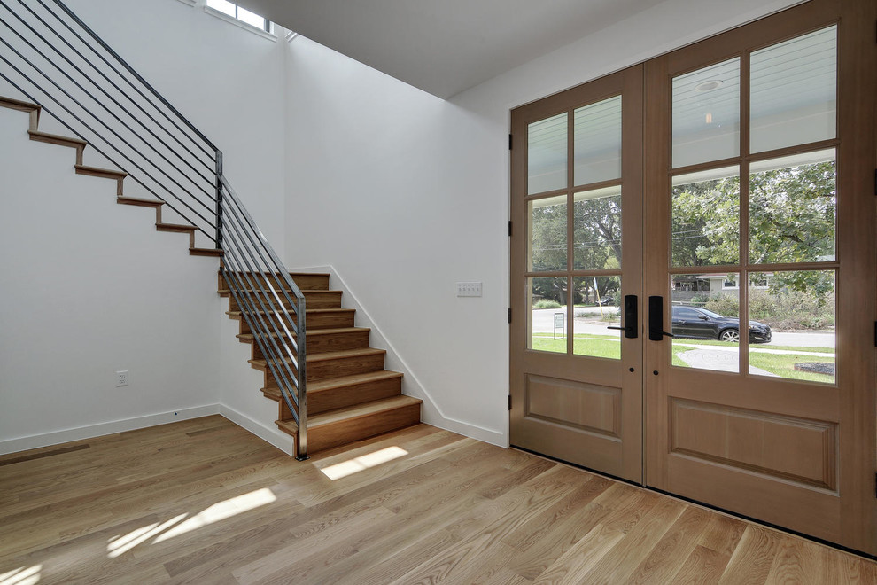 Foto de puerta principal moderna con paredes blancas, suelo de madera clara, puerta doble y puerta de madera clara