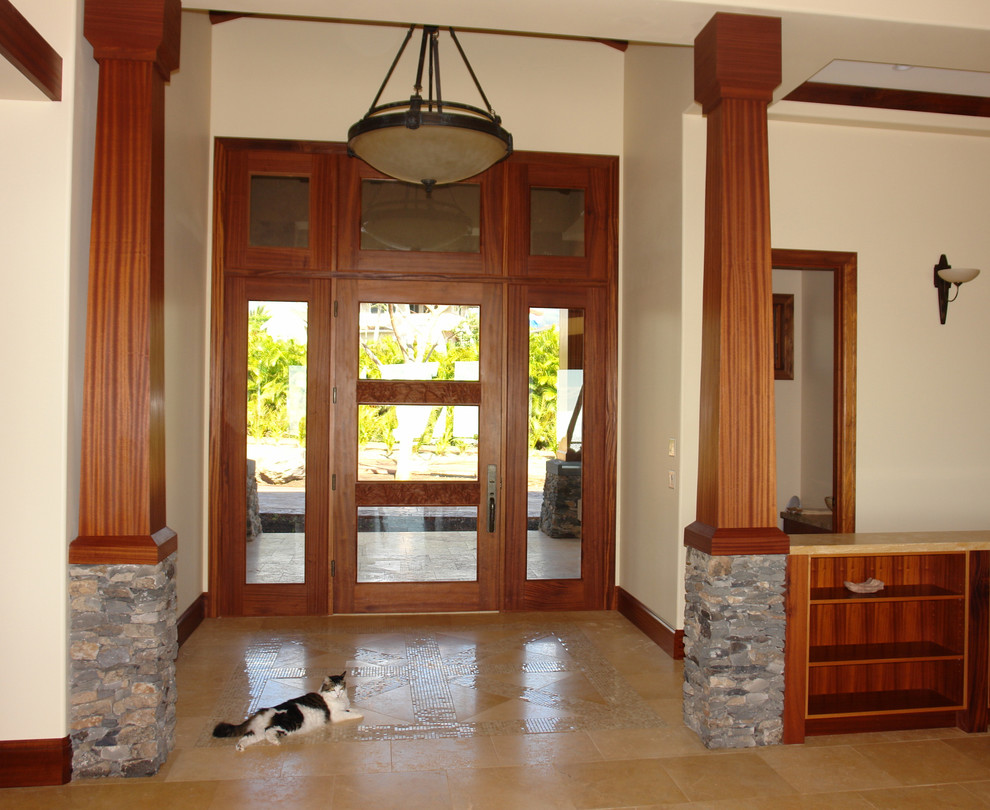 Immagine di un ampio ingresso tropicale con pareti beige, pavimento in pietra calcarea, una porta singola e una porta in legno scuro
