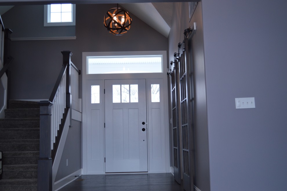 Idée de décoration pour un grand hall d'entrée craftsman avec un mur gris, parquet foncé, une porte simple, une porte blanche et un sol marron.