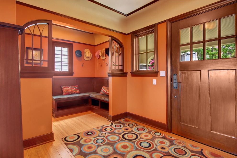 На фото: входная дверь в стиле кантри с оранжевыми стенами, паркетным полом среднего тона, одностворчатой входной дверью и входной дверью из темного дерева с