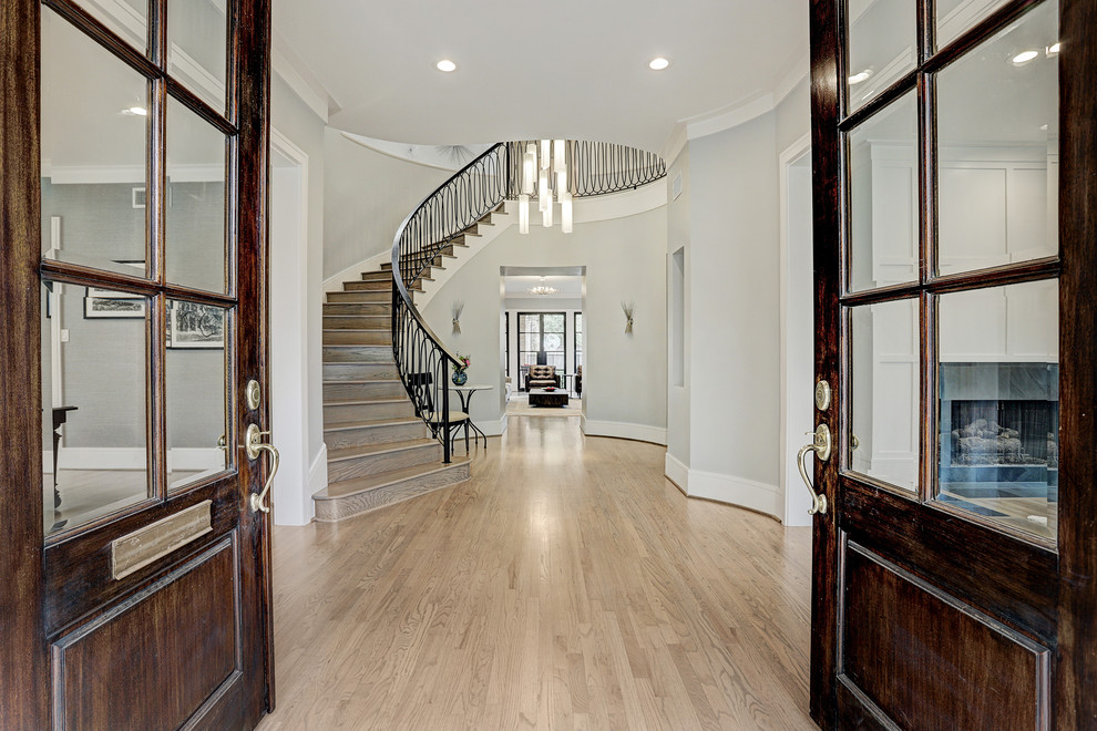 Inspiration for a large transitional light wood floor and white floor entryway remodel in Houston with gray walls and a dark wood front door