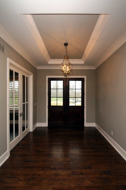 Aménagement d'un hall d'entrée classique de taille moyenne avec un mur gris, parquet foncé, une porte double, une porte en bois foncé et un sol marron.