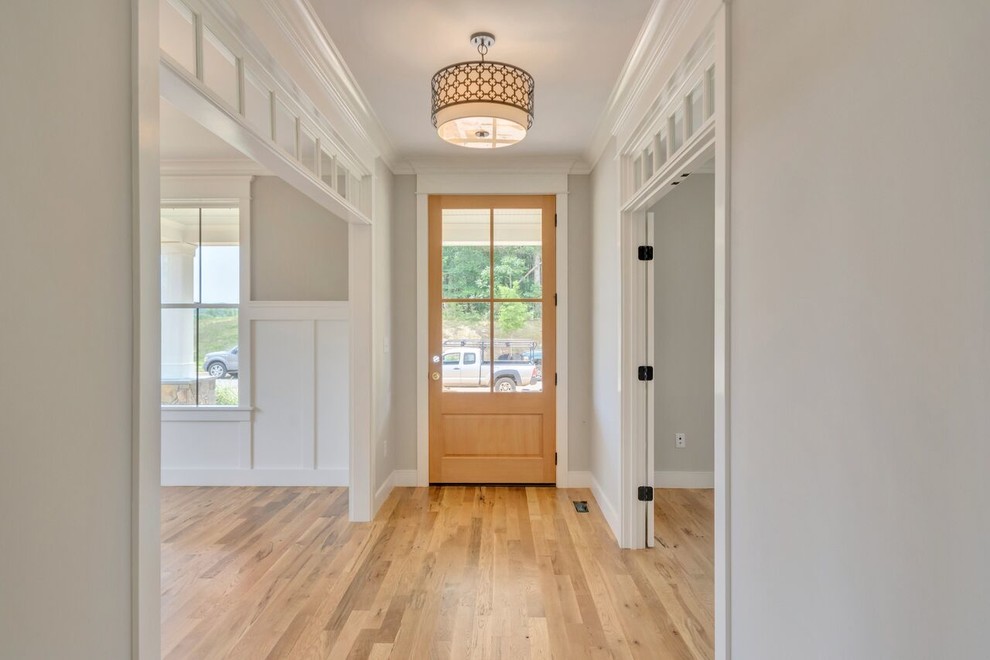Ejemplo de hall de estilo de casa de campo de tamaño medio con paredes grises, suelo de madera clara, puerta simple y puerta de madera clara